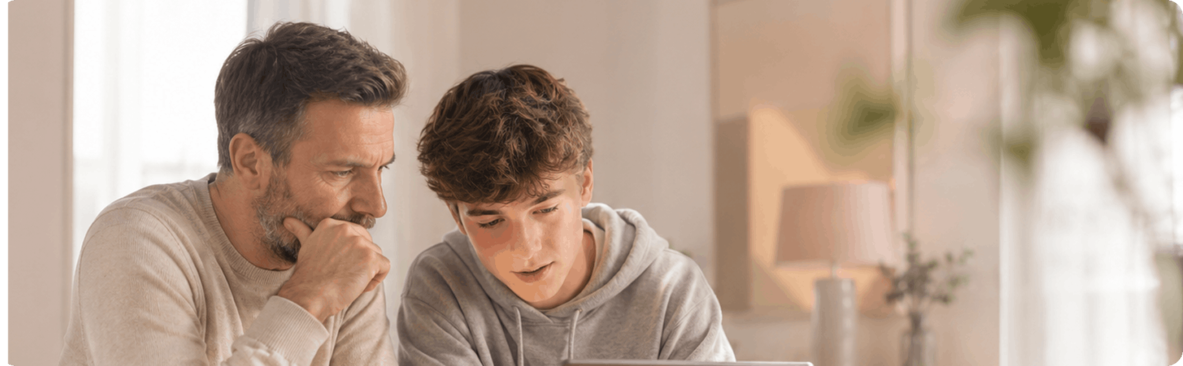A parent and teenager looking at a laptop together