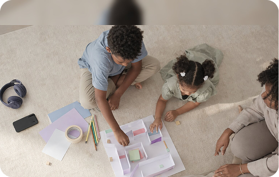 Two children making a craft project on the floor